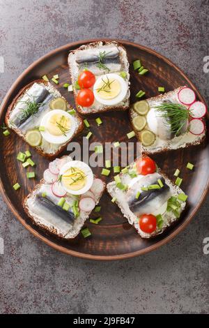 Kiluvoileib Estonian open sandwich consists of a slice of rye bread that is topped with a marinated sprat fillet, eggs, vegetables and herbs close-up Stock Photo