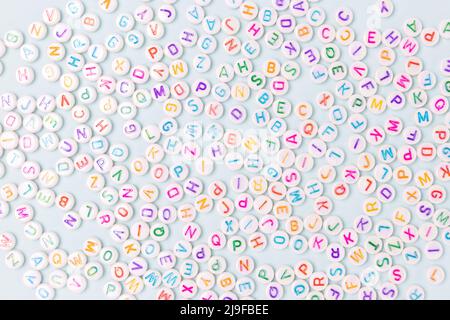 Beads with letters scattered on a blue pastel background. Stock Photo
