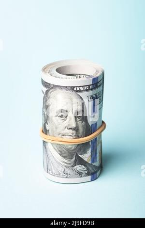 Roll of one hundred american dollars on blue background. Stock Photo