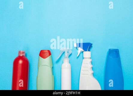House cleaning supplies on blue background. Row of plastic bottles with cleaning liquid and sponges. Cleaning business, production, shopping and deliv Stock Photo