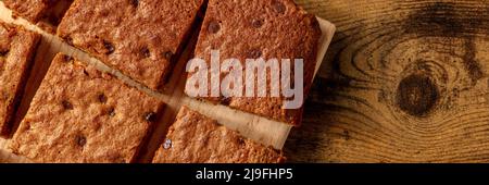 Blondie brownie dessert bars with chocolate chips panorama, shot from the top with a place for text on a dark rustic wooden background Stock Photo