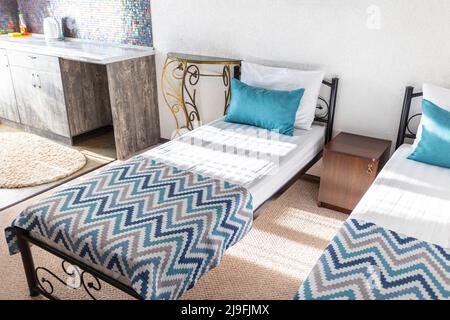 Two beds in a hotel room. white and blue pillows on a white sheet sunbeams Stock Photo