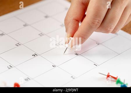 Hands fixing notes schedule, white pin thumbnail in calendar for  meeting and appointment reminder Stock Photo