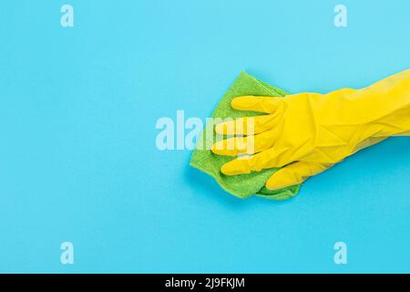 worker's hand in yellow rubber protective glove with micro fiber green sponge or washcloth. A maid or housewife takes care of the house. general or re Stock Photo