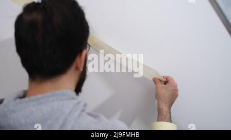 Home repair service master uses masking tape before painting Stock Photo