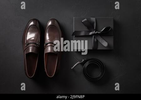 Set of classic mens accessories - shoes, belt and gift on black background. Top view. Flat lay. Concept mens design and Fashion. Father's Day. Stock Photo