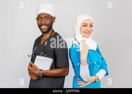 medical team standing together over light gray background. african american surgeon and doctor muslim woman with stethoscopes Stock Photo