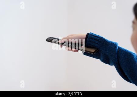 CHIANG MAI, THAILAND - MAY 23, 2022 : Woman with TV remote control in hand using Netflix application on smart TV Stock Photo