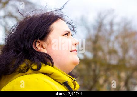 Attractive chubby overweight Caucasian woman smiling portrait outdoors with copy space. Cheerful pretty body positive person during walk in the park. Stock Photo