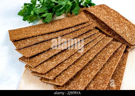 Crispy thin rye bread stack for eating with parsley on wooden board background. Stock Photo