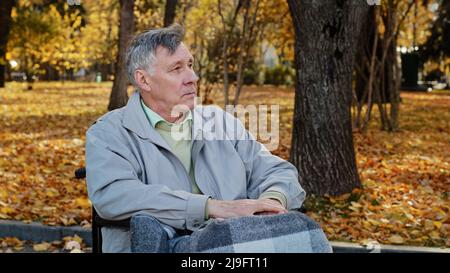 Mature outdoors upset senior retired caucasian man grandfather with disability sit alone at wheelchair depressed pensive old male person in older age Stock Photo