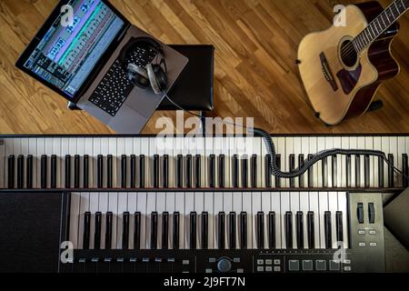Piano keys, top view, musician's workplace with laptop. Stock Photo