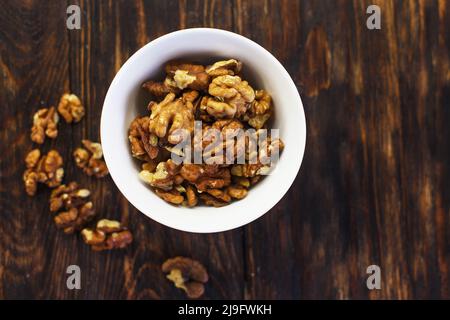 peeled walnuts in the white bowl close on a brown old wooden table. healthy food concept Stock Photo