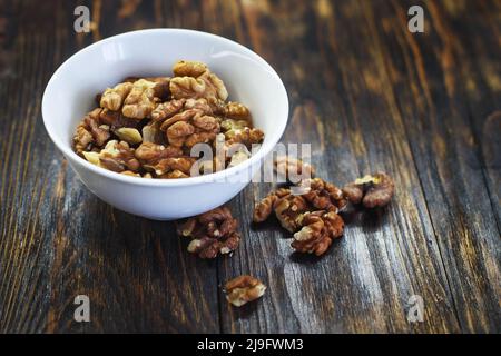 peeled walnuts in the white bowl close on a brown old wooden table. healthy food concept Stock Photo