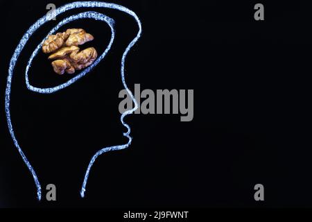 silhouette of person drawn head with nuts and abstraction brain in the form of walnut on a black background. Concept of healthy food for a human to th Stock Photo