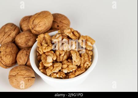 Bowl of walnut kernel with whole walnuts in the background Stock Photo