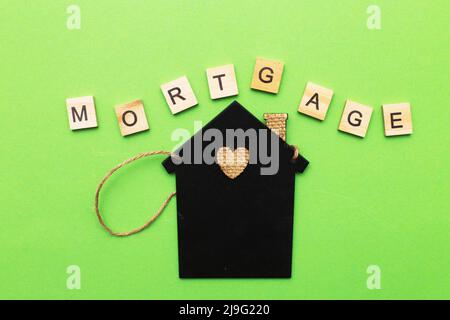 inscription mortgage with a little house on a green background made by wooden blocks. Stock Photo