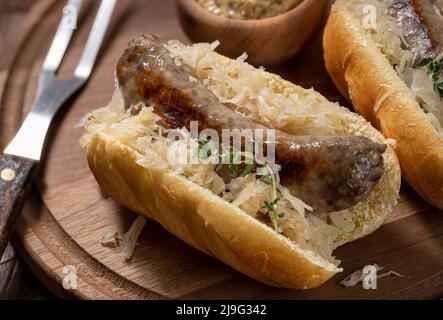 Closeup of bratwurst with sauerkraut on a bun on a wooden cutting board Stock Photo