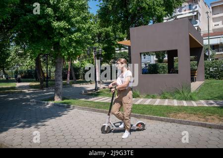 Young woman sitting on her stant-up electric scooter Stock Photo