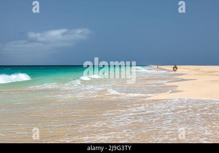 Tourists walking along the idyllic empty white sand beach of Ponta Preta, Santa Maria, Sal Island, Cape Verde, Cabo Verde Islands, Africa Stock Photo