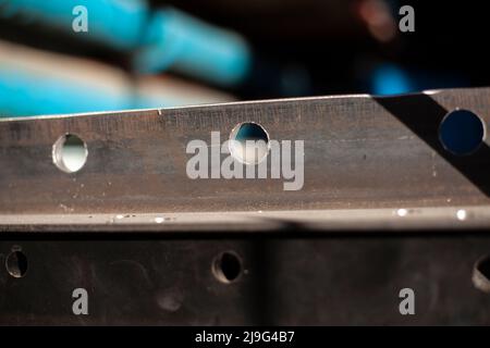 Holes in steel from drilling. Metal blank. Steel profile is drilled with drill in workshop. Iron product. Holes for fastening structure. Stock Photo