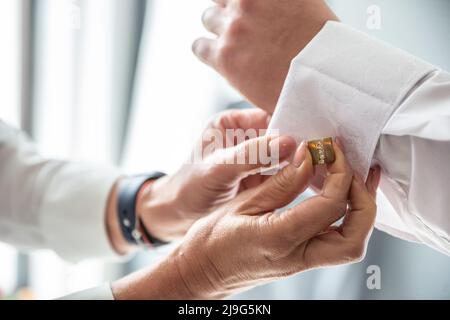Best man helping groom fix cufflinks on his shirt before the wedding ceremony. Stock Photo
