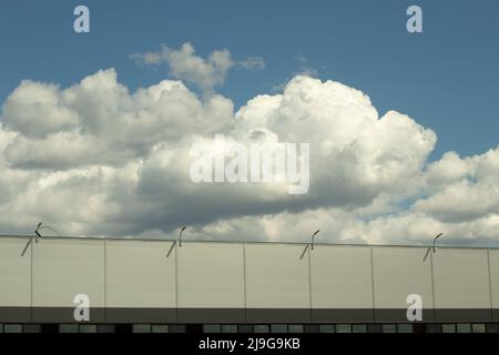 Warehouse and sky. Grey building. Clouds over the warehouse. Modern logistics architecture. Stock Photo
