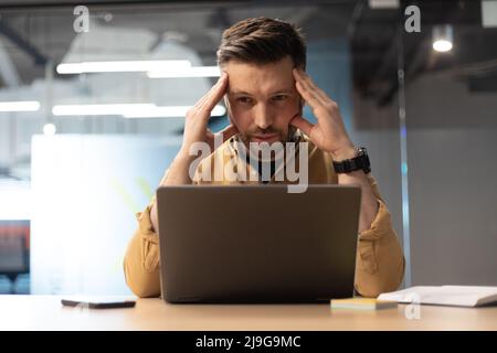 Businessman Using Laptop Suffering From Headache Having Problems In Office Stock Photo
