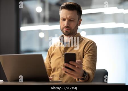 Businessman Texting On Phone Reading Negative Message Working In Office Stock Photo
