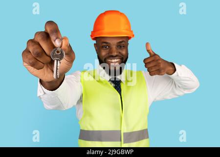 Happy Black Builder Wearing Hardhat Holding Keys And Gesturing Thumb Up Stock Photo