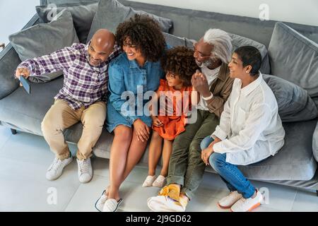 Happy family sitting on sofa while taking selfie Stock Photo