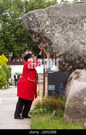 London, UK. 23 May 2022. A Chelsea Pensioner on the Adrian Gray Stonebalancing Sculptures stand, during the RHS Chelsea Flower Show press day, at the Royal Hospital Chelsea, London. Picture date: Monday May 23, 2022. Photo credit should read: Matt Crossick/Empics/Alamy Live News Stock Photo