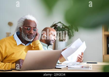 Father and son using laptop and reading documents Stock Photo