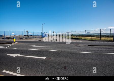 Looking across to the harbour railway station access road which lies between fenced off & disused former ferry port land and facilities. Stock Photo