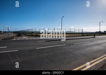 Looking across to the harbour railway station access road which lies between fenced off & disused former ferry port land and facilities. Stock Photo