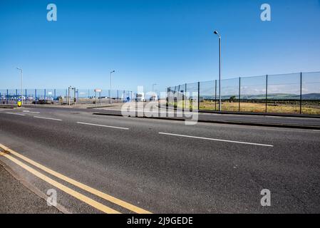 Looking across to the harbour railway station access road which lies between fenced off & disused former ferry port land and facilities. Stock Photo