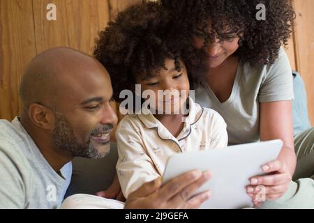 Parents with daughter using digital tablet in bedroom Stock Photo