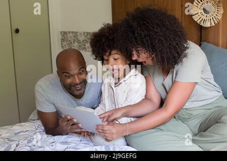 Parents with daughter using digital tablet in bedroom Stock Photo