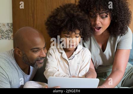 Parents with daughter using digital tablet in bedroom Stock Photo