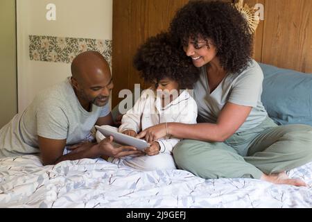 Parents with daughter using digital tablet in bedroom Stock Photo