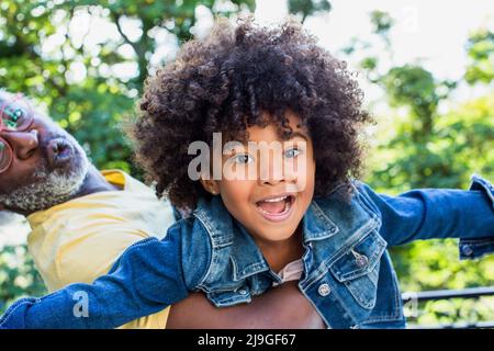 Smiling granddaughter playing with her grandfather in balcony Stock Photo