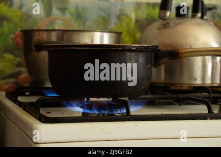 a dirty saucepan stands on a dirty gas stove in the kitchen at home, cooking soup on the stove, gas stove, kitchen Stock Photo