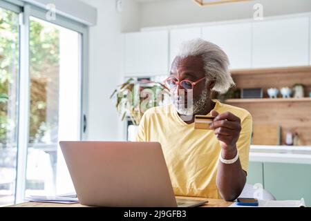 Senior man using laptop and credit card Stock Photo