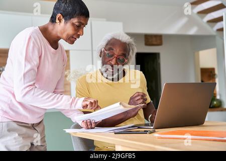 Couple using laptop in kitchen Stock Photo