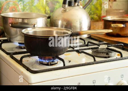 a dirty saucepan stands on a dirty gas stove in the kitchen at home, cooking soup on the stove, gas stove, kitchen Stock Photo