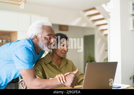 Couple using laptop in kitchen Stock Photo