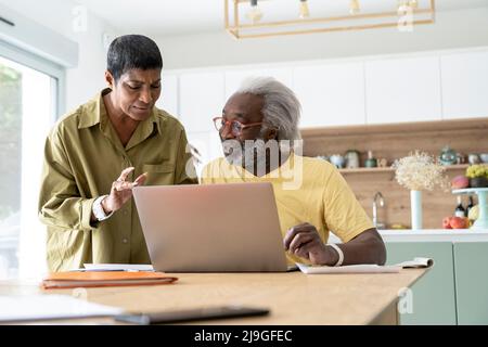 Couple using laptop in kitchen Stock Photo