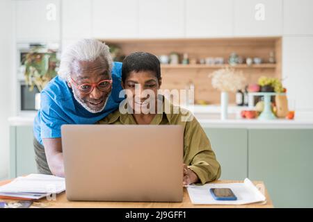 Couple using laptop in kitchen Stock Photo