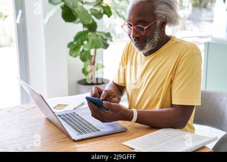 Senior man using smart phone and laptop Stock Photo