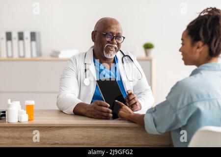 Experienced black doctor explaining treatment plan to female patient Stock Photo
